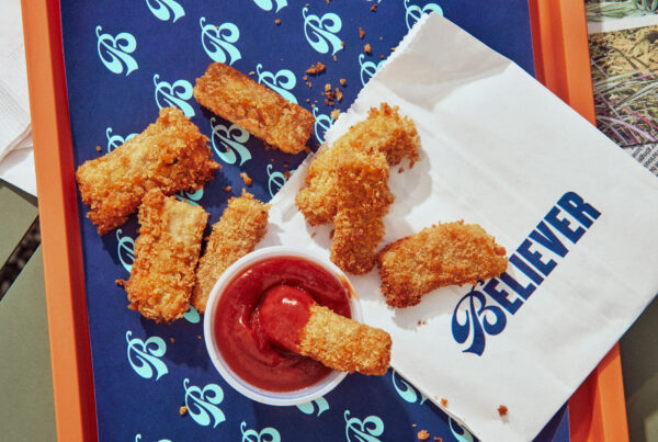 Crispy chicken tenders with ketchup on a patterned tray with napkin.