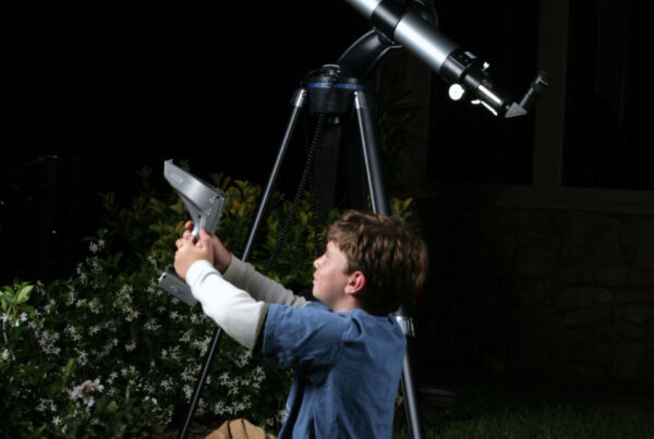 Boy adjusting telescope in backyard at night for stargazing