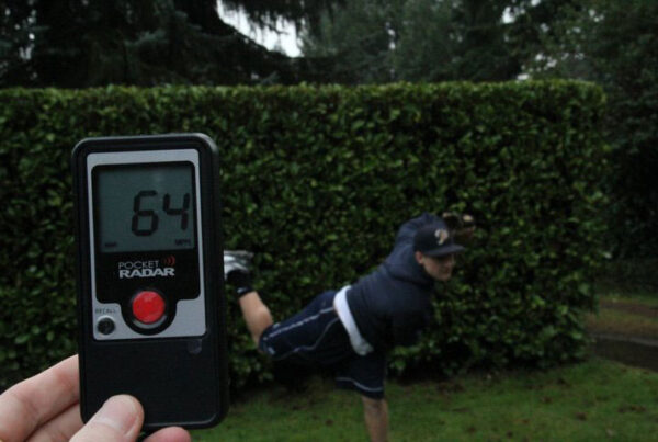Handheld radar device showing 64 mph speed with blurry runner in background