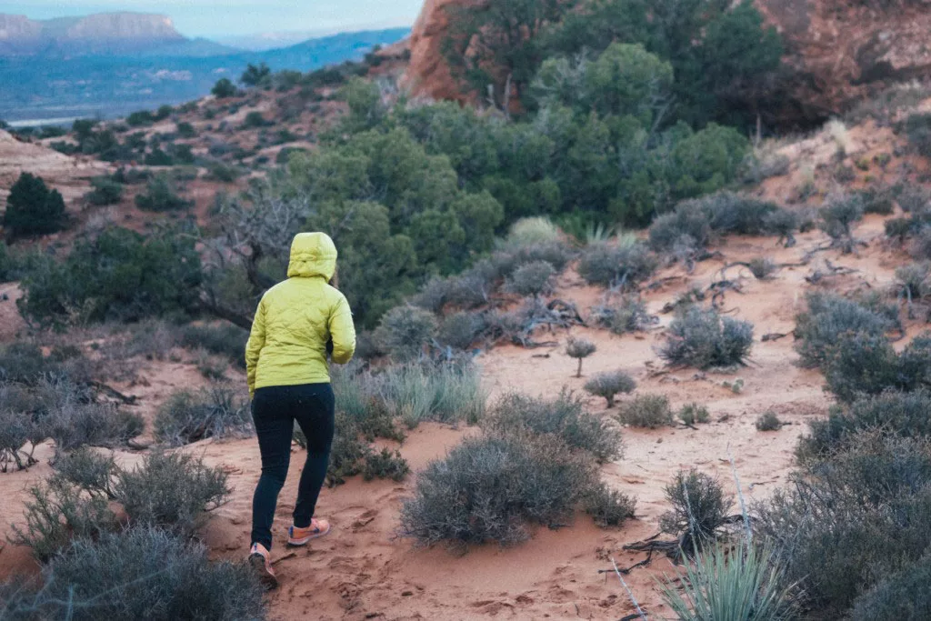 Person in yellow jacket hiking in desert landscape at dusk