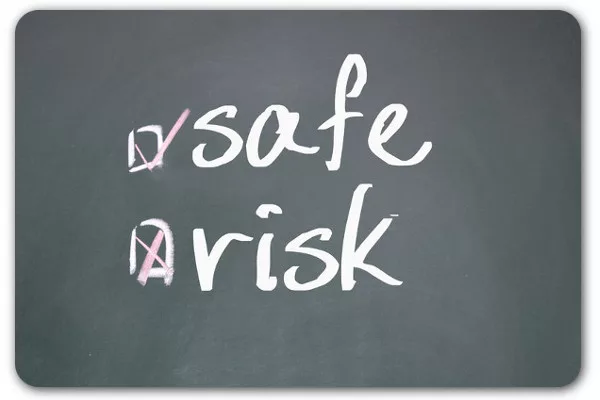 Chalkboard with words 'safe' checked off and 'risk' crossed out indicating decision making