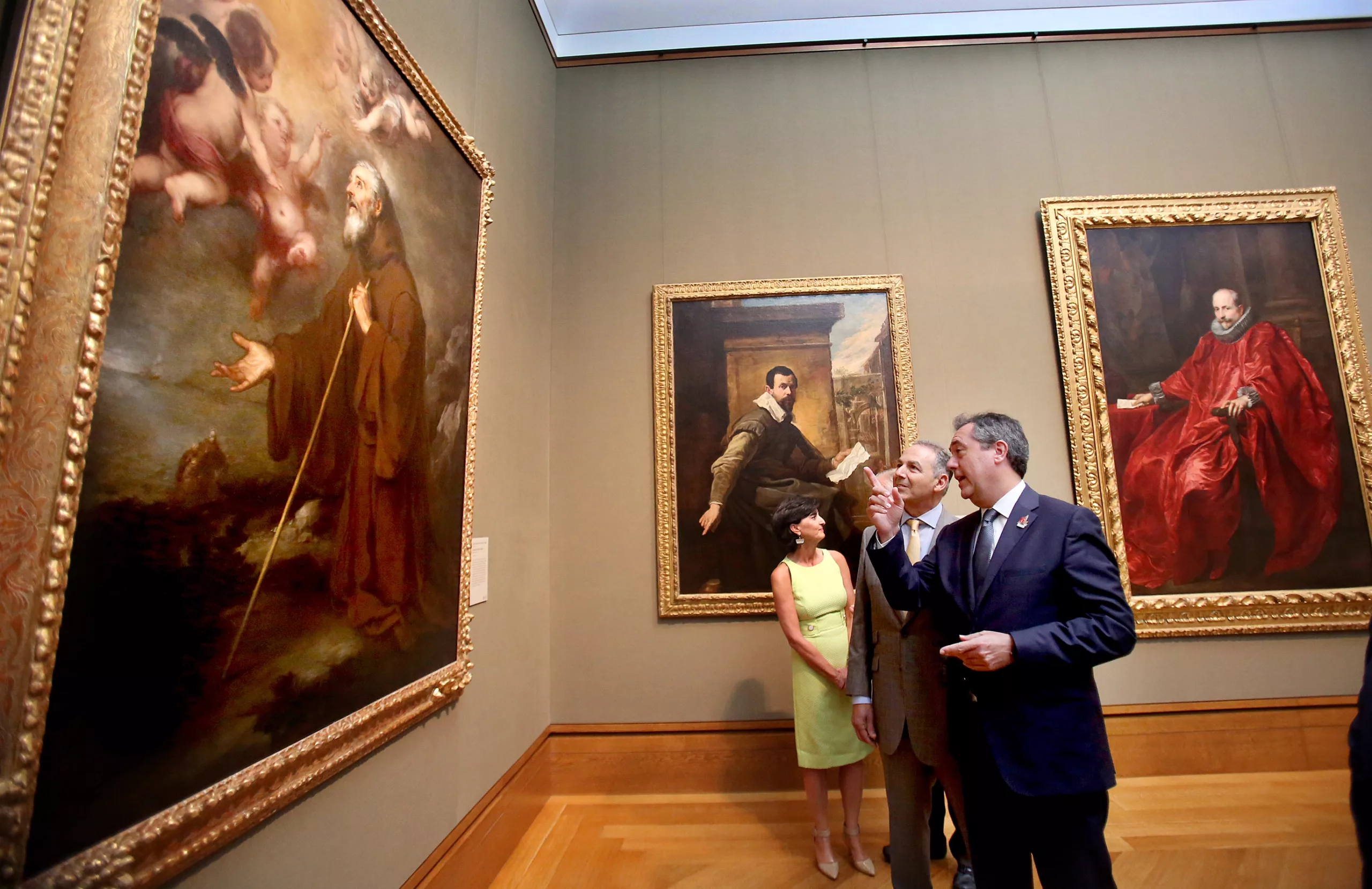 Visitors viewing classic paintings in an art gallery setting.