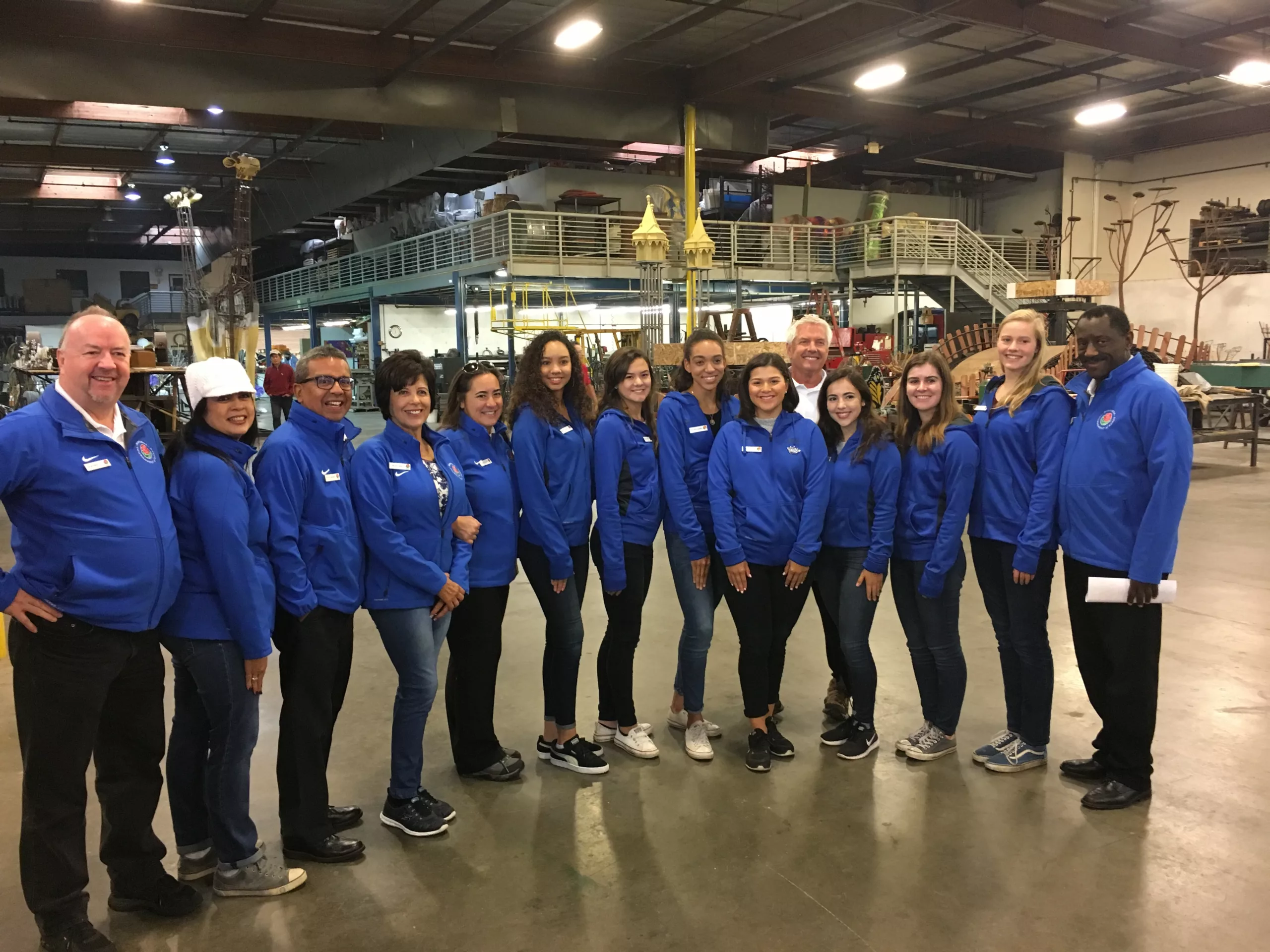 Group of employees in blue jackets smiling in a workshop setting