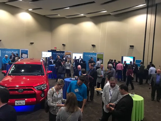 Indoor trade show event with attendees networking and red Toyota truck display