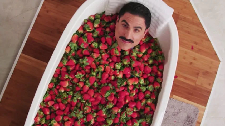 Man with mustache in bathtub full of strawberries