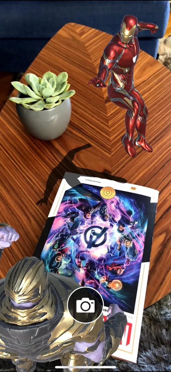 Iron Man AR figure hovering over comic book next to Thanos and succulent.