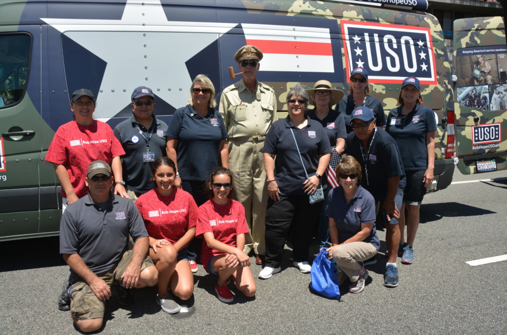 Group of volunteers posing in front of a USO tour vehicle.