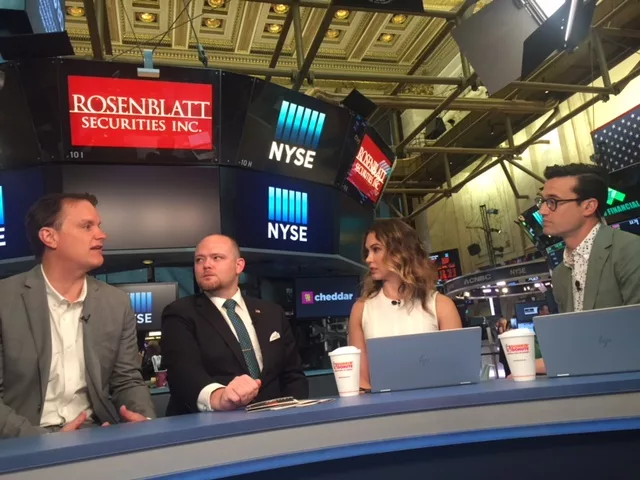 Four professionals discussing at a desk with NYSE and Rosenblatt Securities signage in background