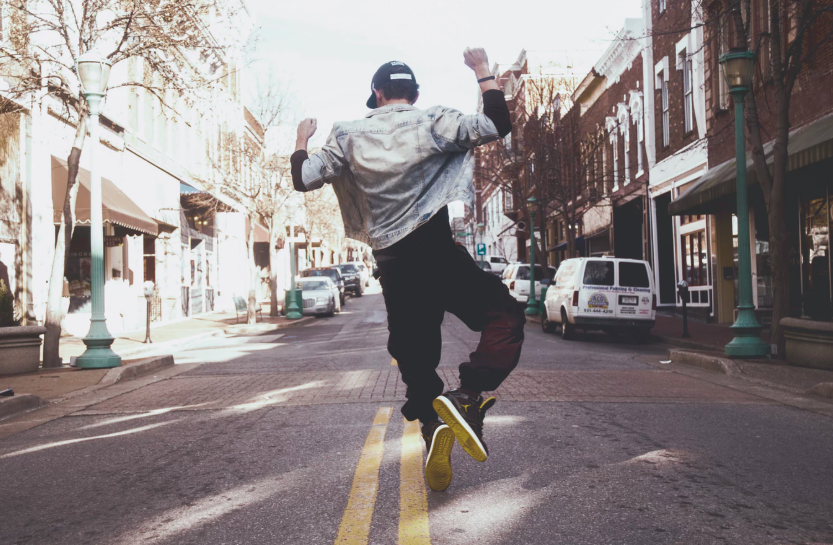 Man jumping with joy in the middle of an empty urban street