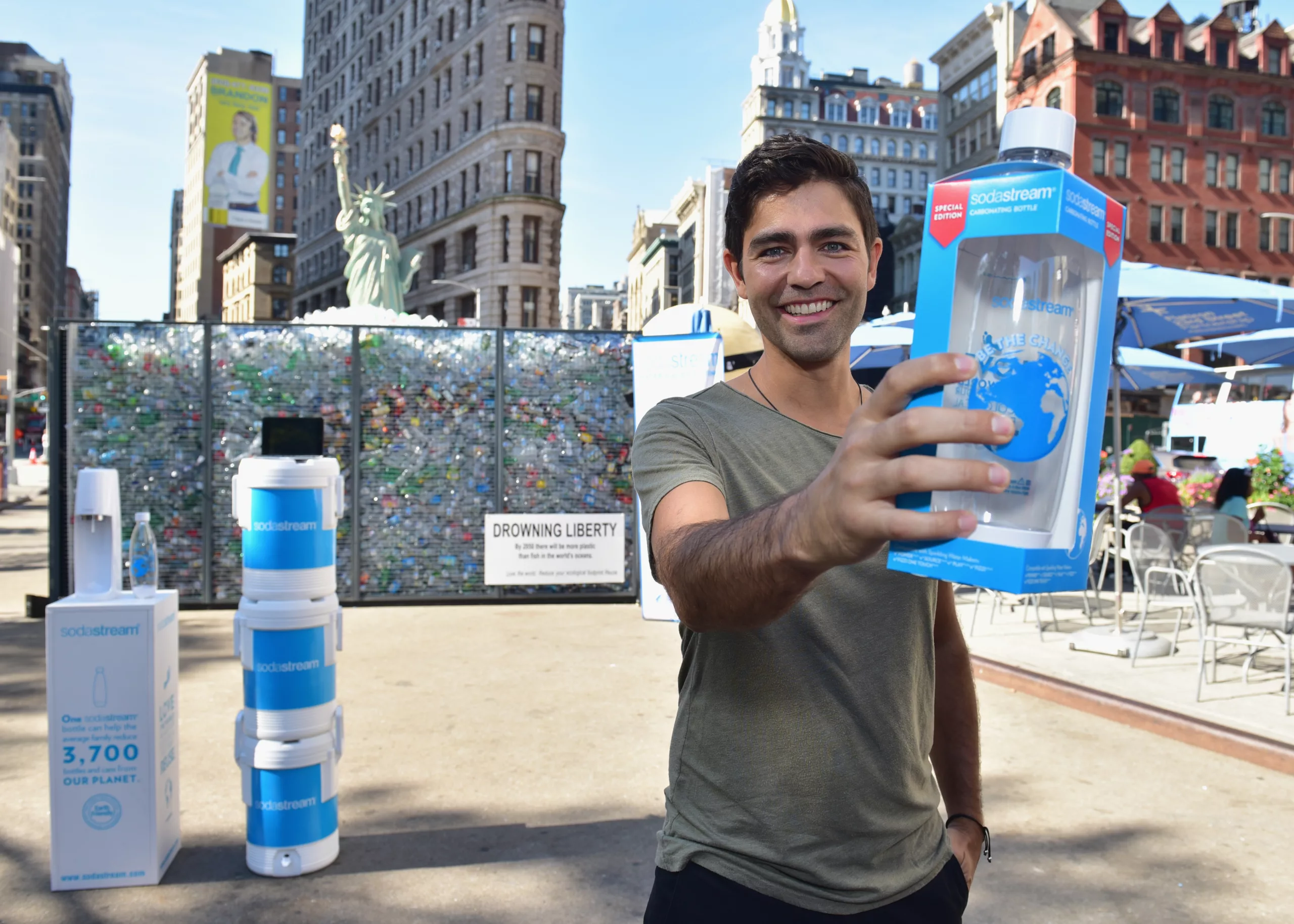 Man smiling with SodaStream bottle in front of recycling exhibit