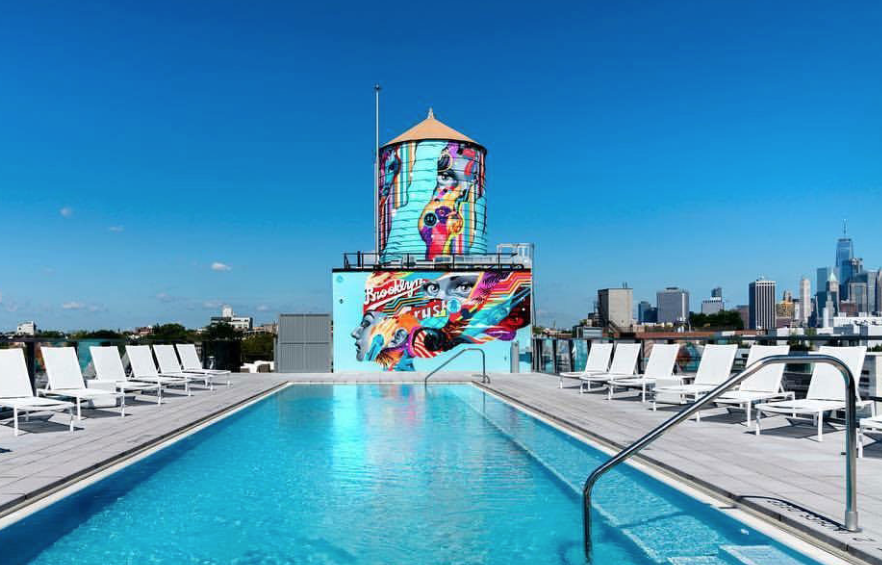 Rooftop pool with colorful graffiti water tower and city skyline in the background