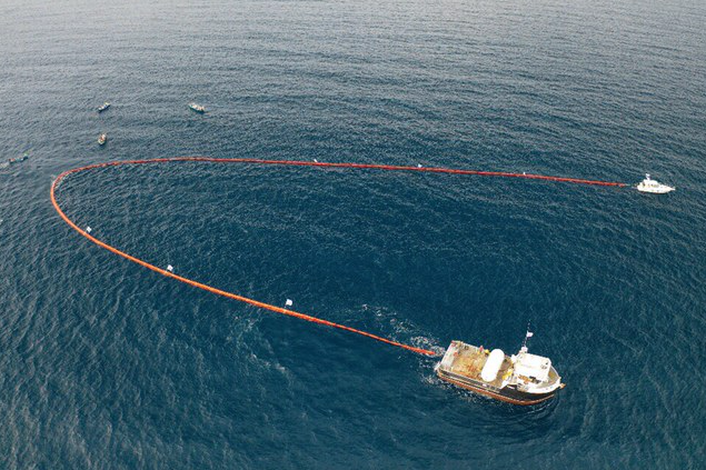 Ocean cleanup system with a long barrier and support boat from above