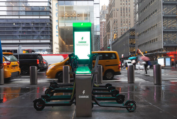 Electric scooter charging station in rainy city with pedestrians and taxis