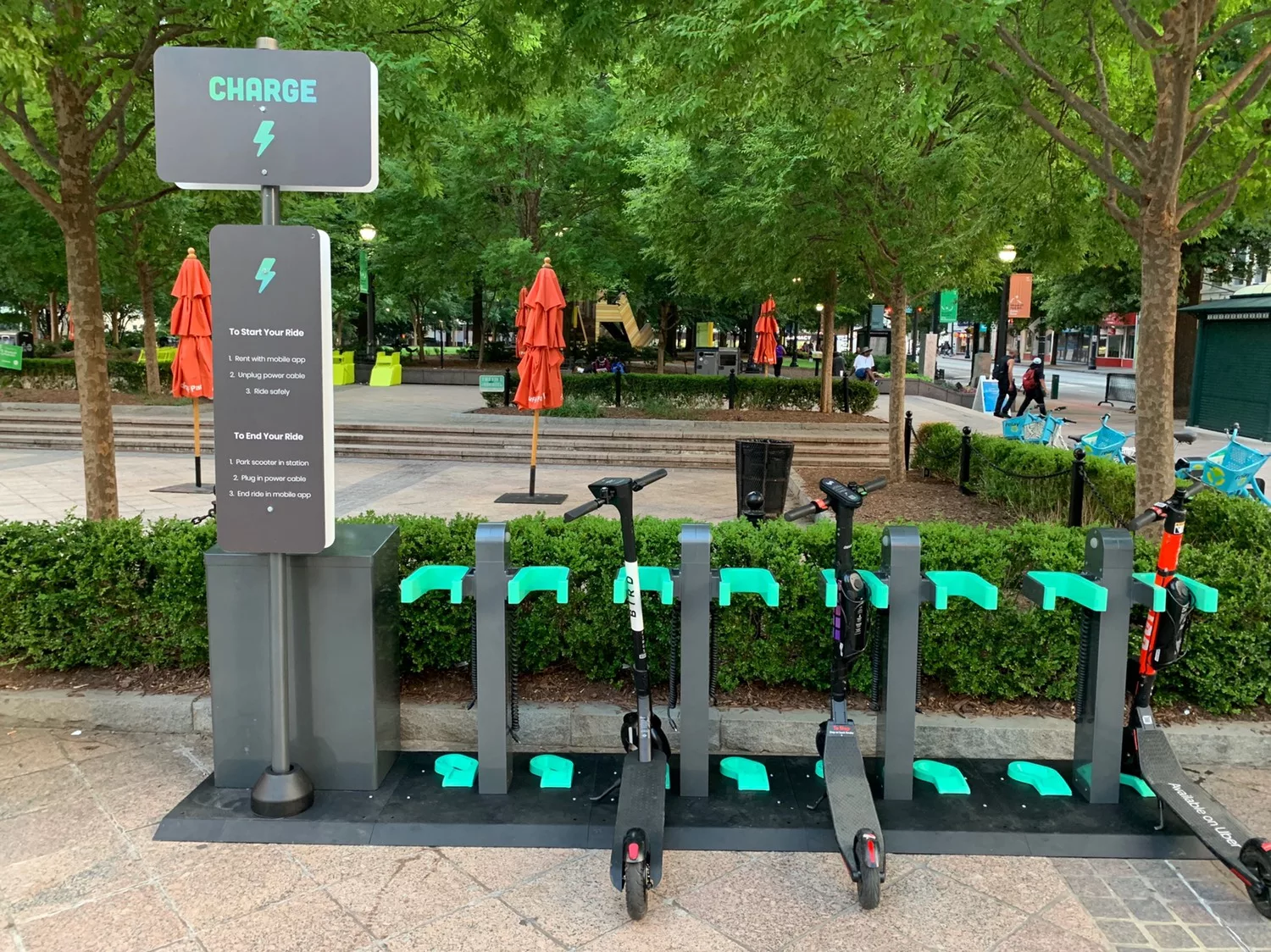 Electric scooter charging station with instructions sign in urban park setting