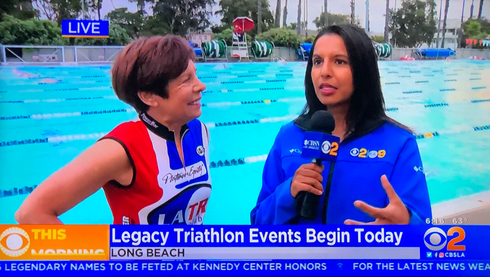 Reporter interviews athlete at Legacy Triathlon event in Long Beach beside pool.