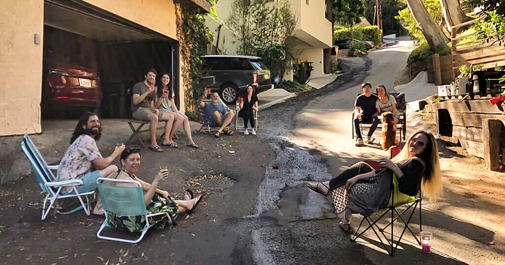 Group of friends enjoying drinks on a sunny driveway with lawn chairs