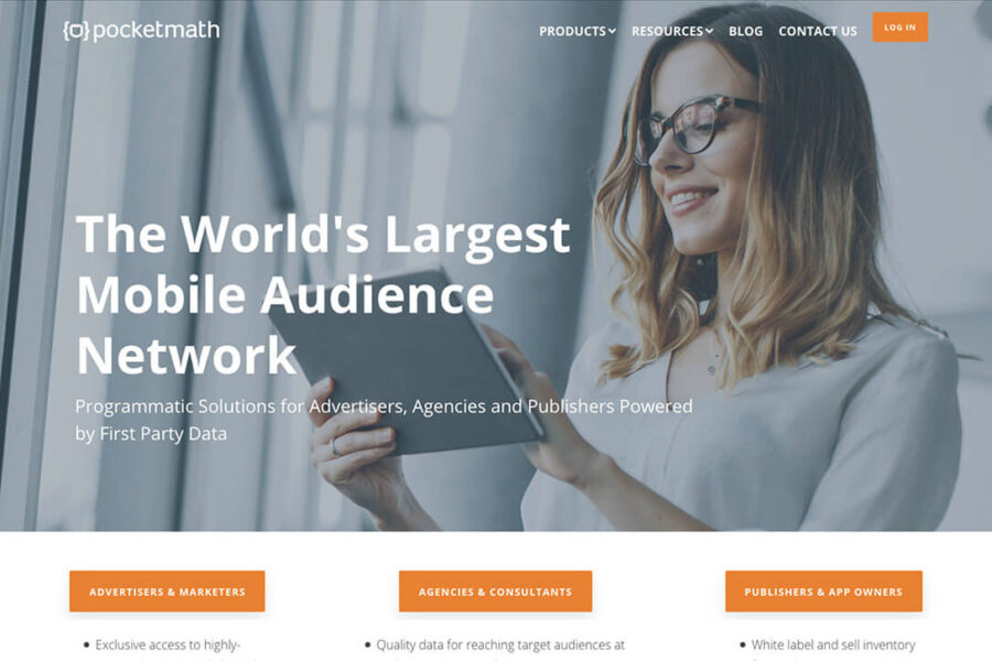 Woman using a tablet with text "The World's Largest Mobile Audience Network" on screen; modern office setting.
