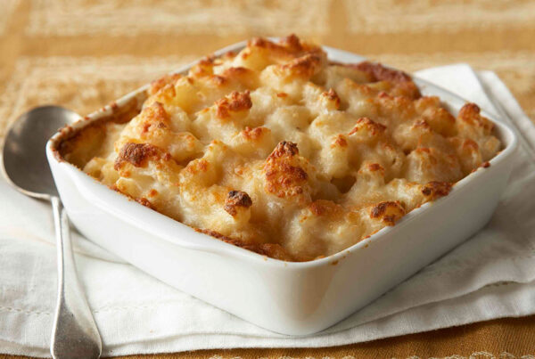 Baked macaroni and cheese in white casserole dish with golden crust