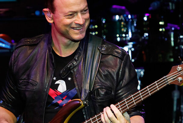Smiling bass player in leather jacket performing on stage