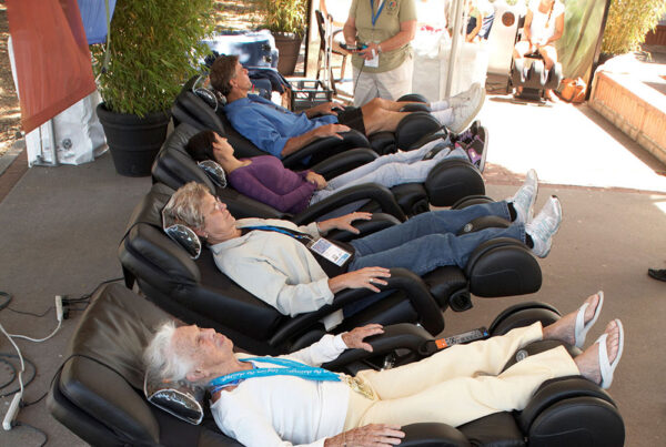People relaxing in massage chairs at an outdoor event