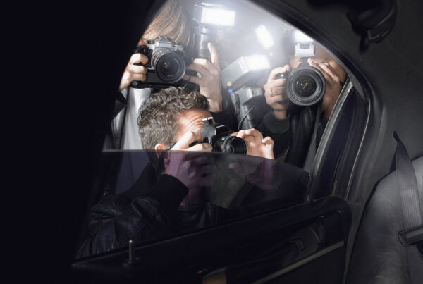 Paparazzi taking photos of celebrity in car at night
