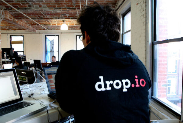 Man in hoodie with logo at bright office with exposed brick walls