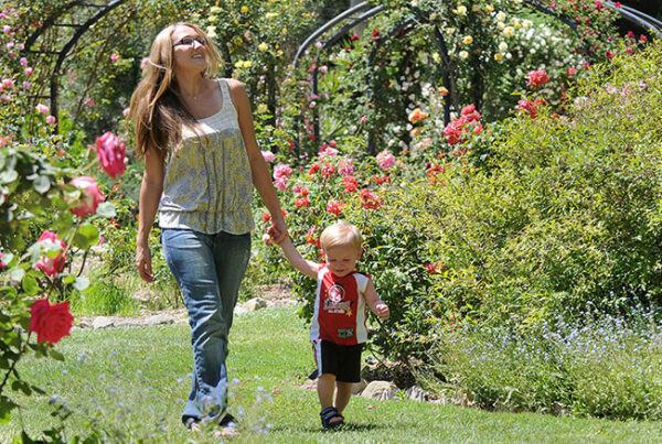 Woman and toddler walking in sunny flower garden path