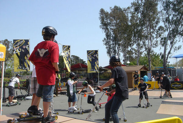 Kids enjoying skateboarding in a park with safety gear and banners in the background