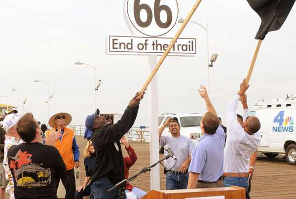 Group of people celebrating at Santa Monica Route 66 end of trail sign