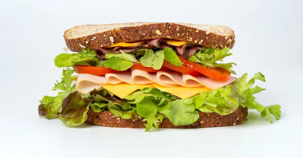 Fresh turkey and cheese sandwich with lettuce and tomato on whole grain bread.