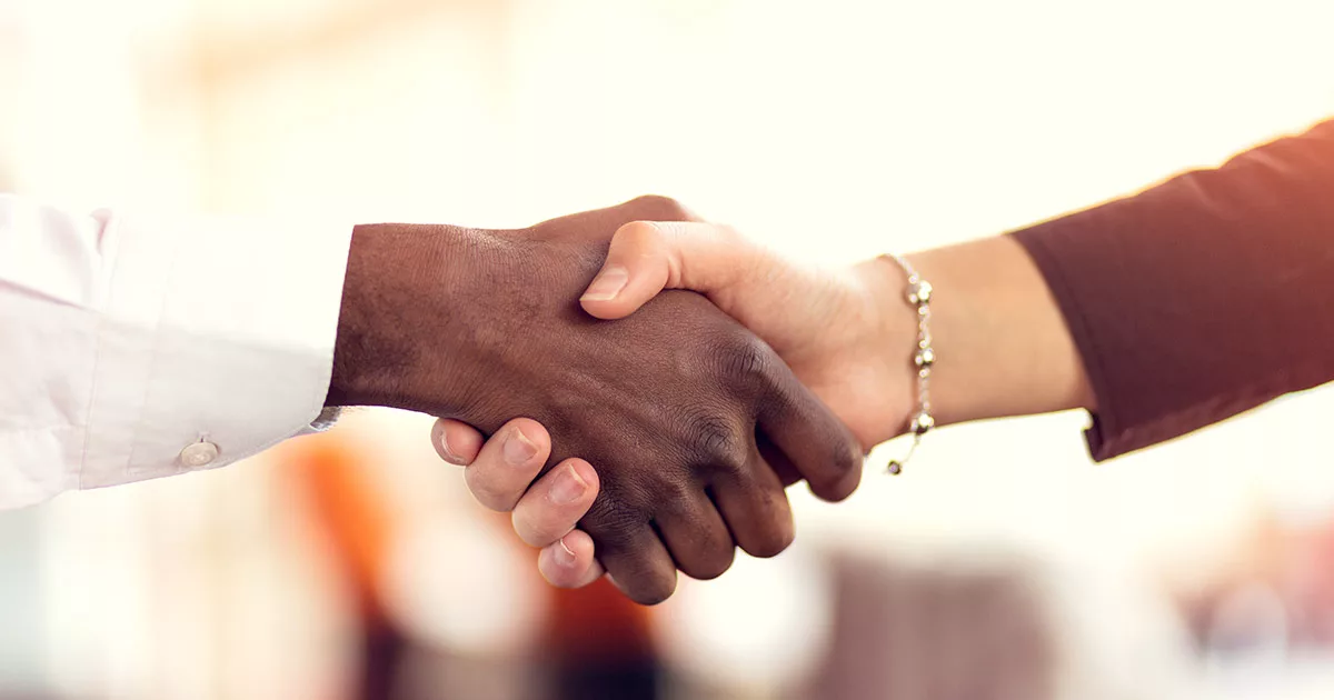 Close-up of diverse handshake in office setting