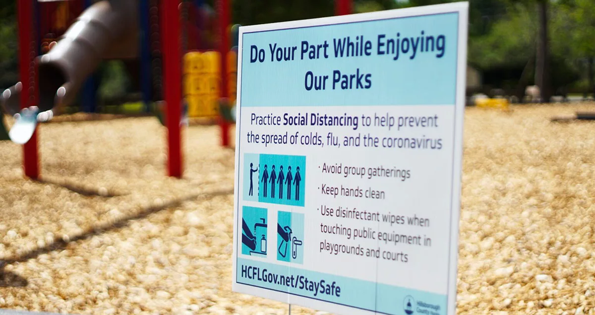 Social distancing park sign with playground in background