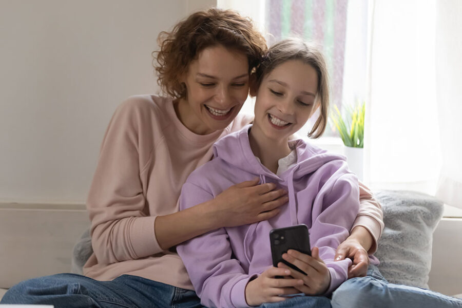 Mother and daughter laughing and looking at a smartphone screen