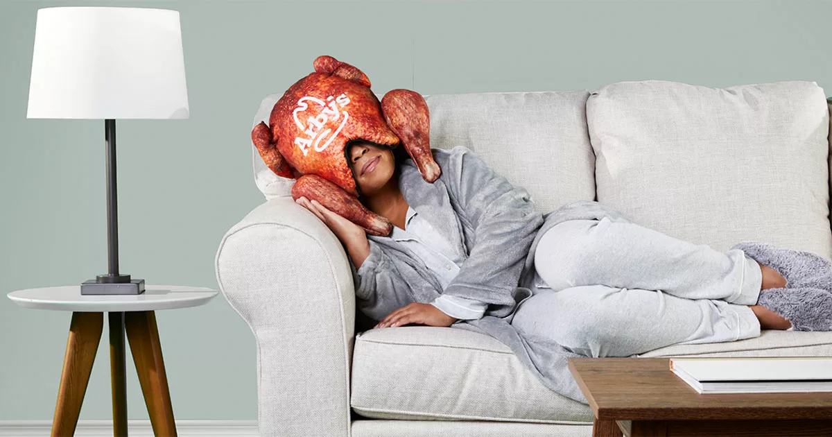 Woman relaxing on sofa with novelty turkey pillow on her head