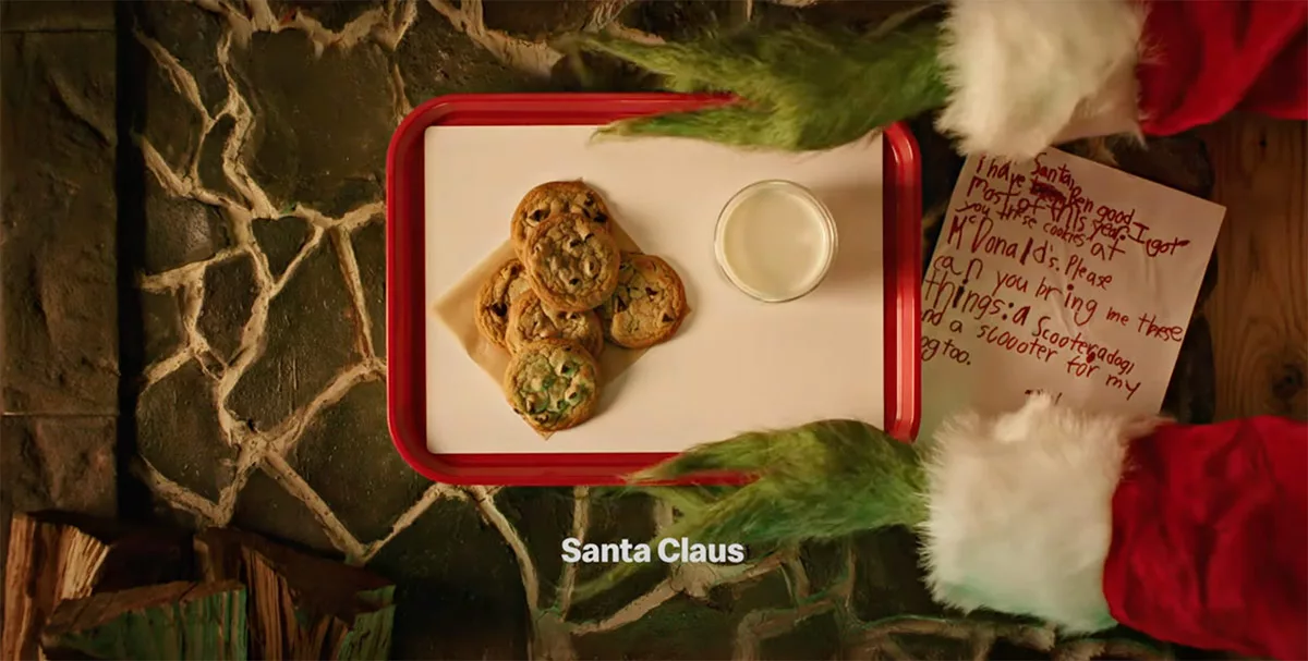 Cookies and milk on tray with Santa's hand and child's wishlist note on Christmas.