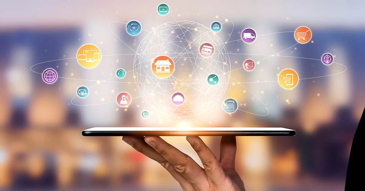 Hand holding tablet with digital icons representing internet of things (IoT) concept on city background