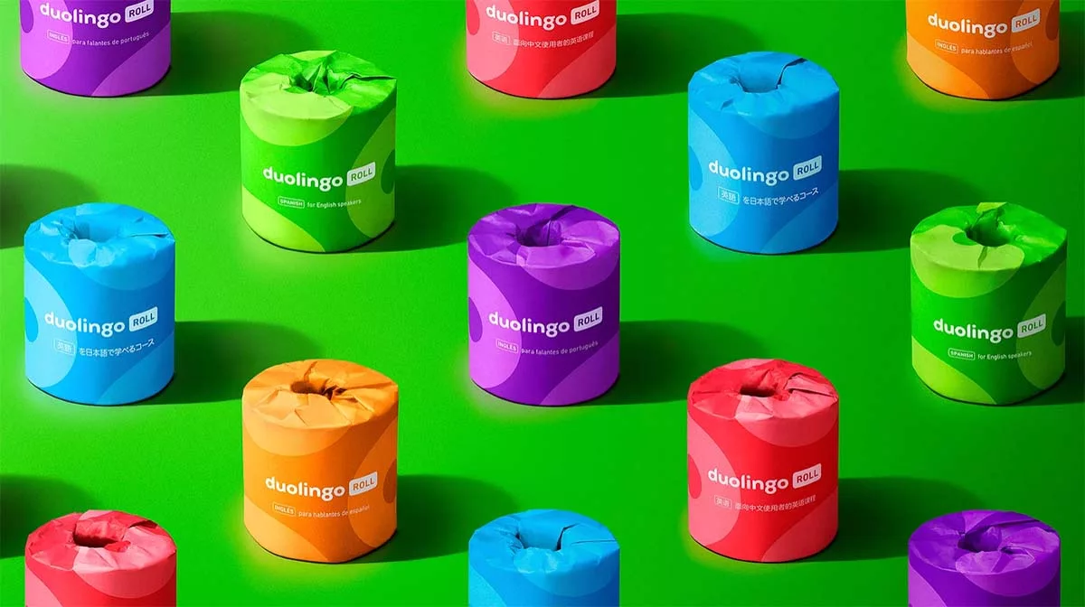 Assorted colorful Duolingo Roll toilet papers on green background.