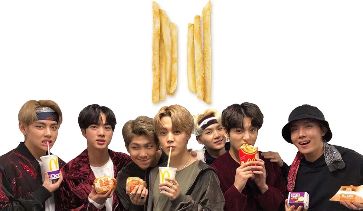 Group of people posing with fast food items and golden fries arranged in an 'M' shape above.