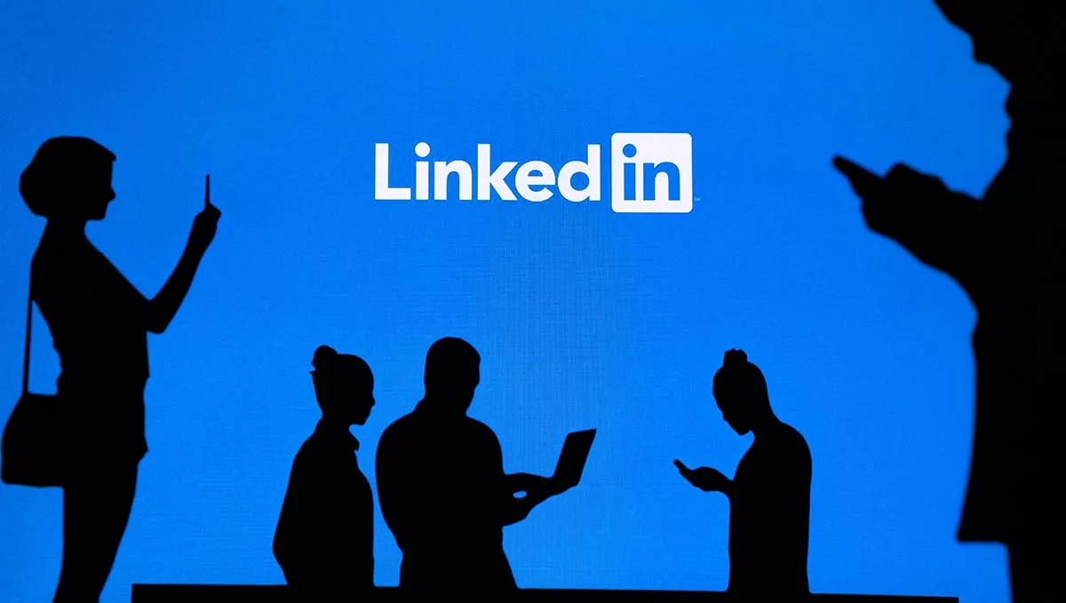 Silhouettes of people using smartphones with LinkedIn logo in background