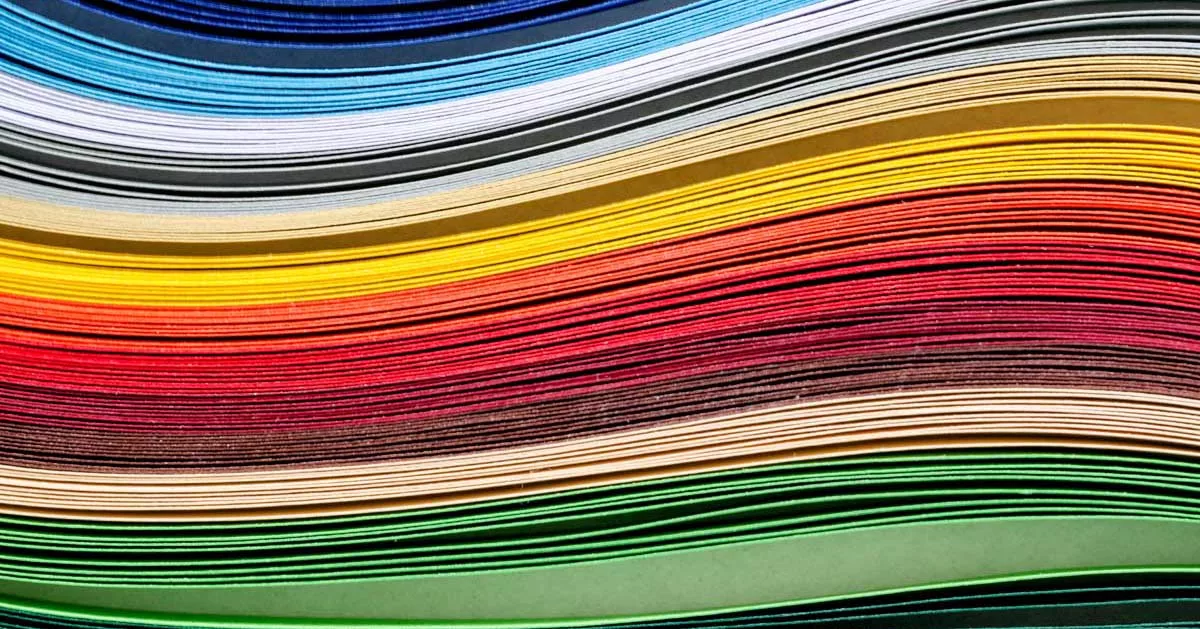 Colorful paper stacks in a gradient from blue to green creating rainbow effect.