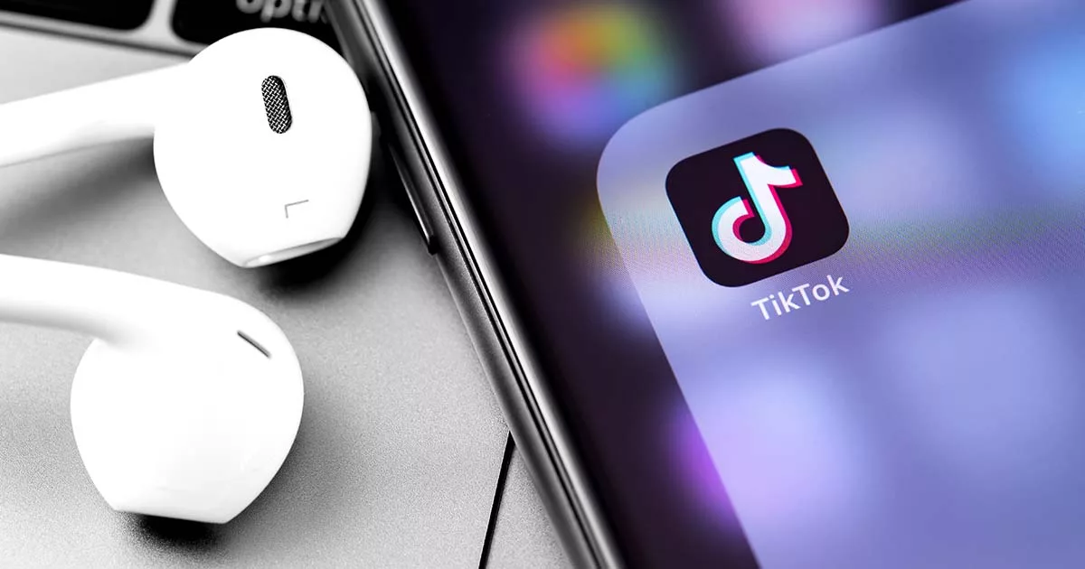Earbuds next to a smartphone with TikTok logo on screen