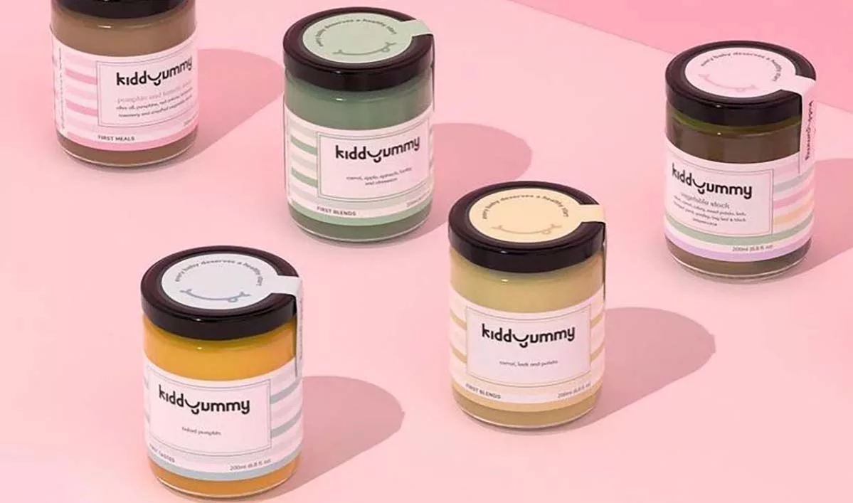 Assorted jars of KiddyYummy baby food on a pink background.