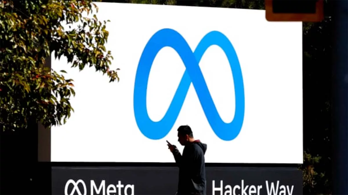 Person pointing at Meta sign on billboard at Hacker Way.