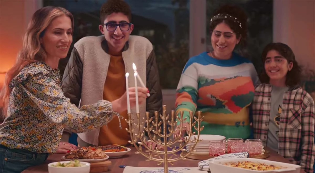 Family lighting Hanukkah menorah with candles