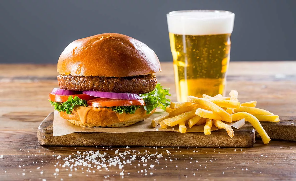 Juicy beef burger with fries and beer on wooden table