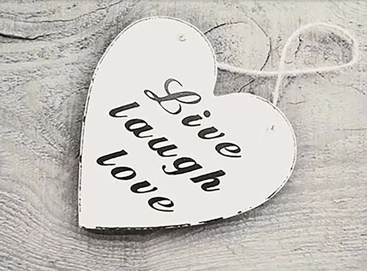 Wooden heart sign with 'Live laugh love' inscription on textured background.