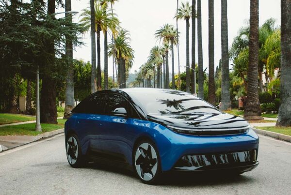 Blue electric car on palm-lined street with reflections on hood