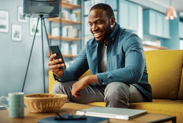 Smiling man using smartphone on yellow couch in a stylish living room