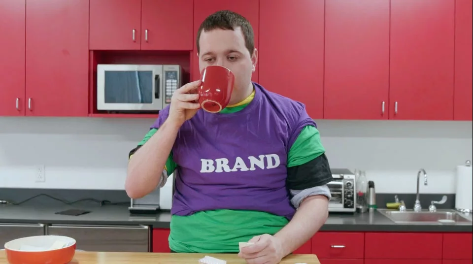 Man in branded shirt drinking coffee in modern red kitchen