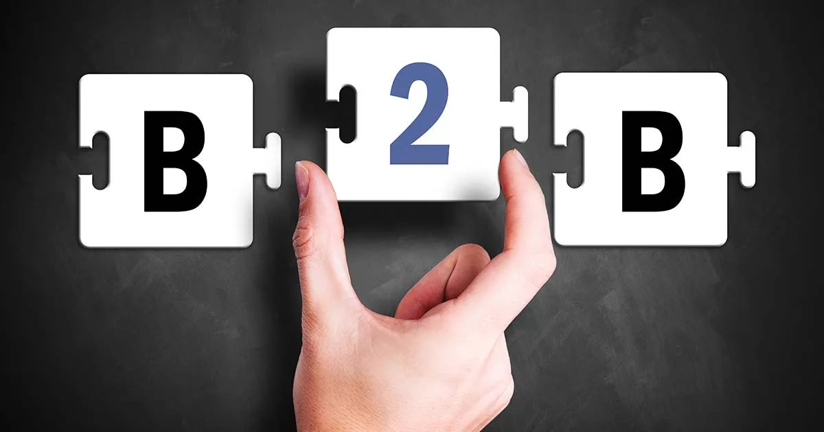 Hand connecting puzzle pieces with letter B and number 2 on a chalkboard background.